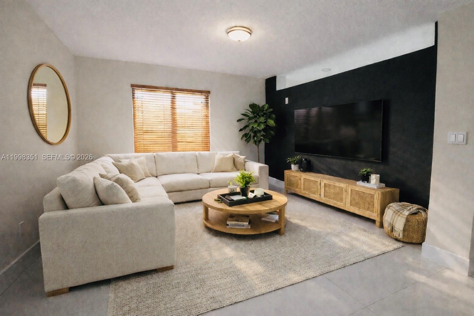 A living room features a white sectional sofa, a round wooden coffee table, and a black accent wall — 9069 NW 193rd St, Hialeah FL 33018, HIALEAH, FL
