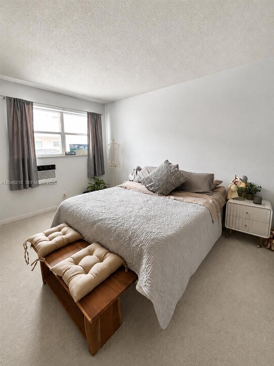 A bedroom features a bed with a gray quilt, a wooden bench, and a nightstand — 3501 Van Buren St # 6, Hollywood FL 33021, HOLLYWOOD, FL