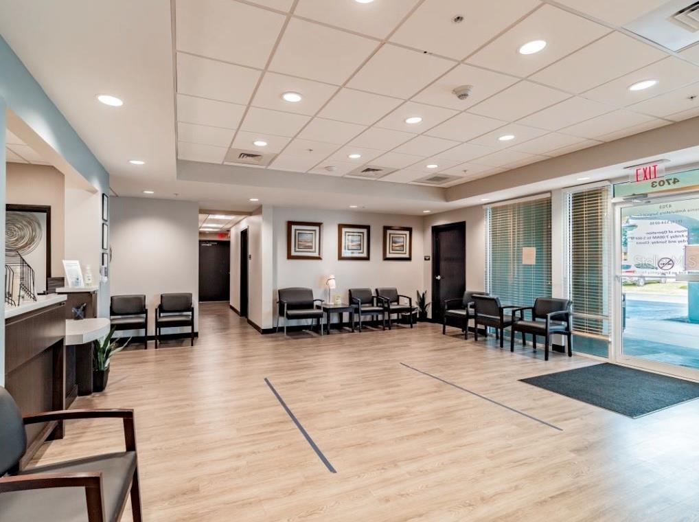 A waiting room features wood-look flooring, rows of black chairs, and a glass exit door — 4703 N ARMENIA AVENUE, TAMPA, FL