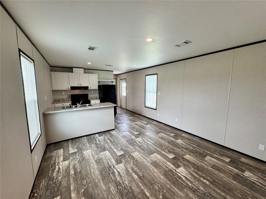 An open-concept kitchen and living area features light-colored walls, wood-look flooring, and white cabinetry — 1115 NW 12TH LANE, LAKE PANASOFFKEE, FL