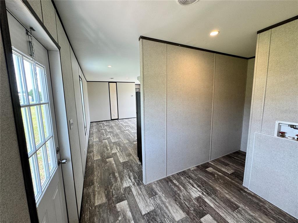 An interior view showing a doorway, wood-look flooring, and a laundry hookup area — 1115 NW 12TH LANE, LAKE PANASOFFKEE, FL
