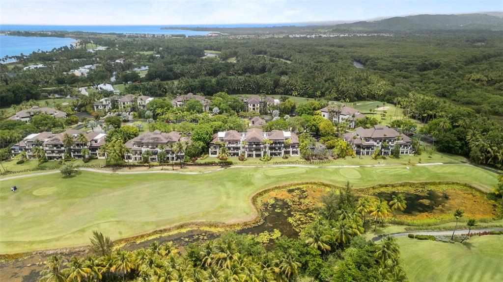 An aerial view shows multi-story residential buildings situated along a golf course and a pond — 8164 LAS VERANDAS AT BAHIA BEACH RESORT, RIO GRANDE, PR