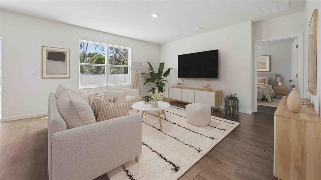 A bright living room features a sofa, area rug, television, and light wood flooring — 1120 GULL DRIVE, APOPKA, FL