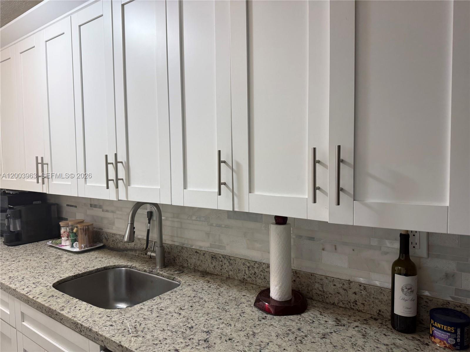 A kitchen features white shaker cabinets, granite countertops, a stainless steel sink, and tile backsplash — 5033 NW 7th St # 312, Miami FL 33126, MIAMI, FL