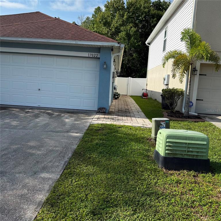 The exterior of two adjacent houses features a paved walkway between them and utility boxes — 17022 HOLMBY COURT, LAND O LAKES, FL
