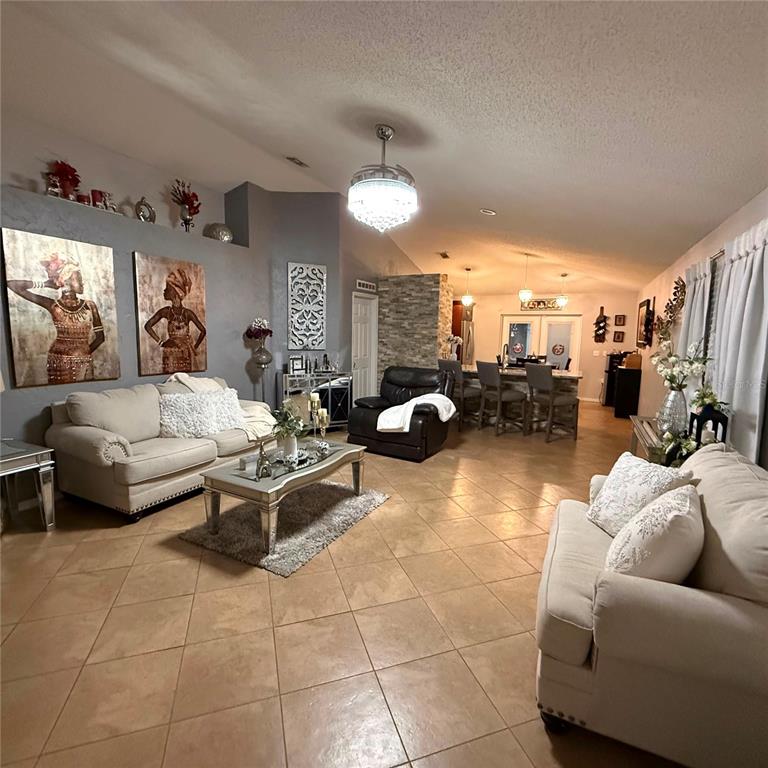 A living room with tile floors, two beige sofas, and an open kitchen area — 17022 HOLMBY COURT, LAND O LAKES, FL