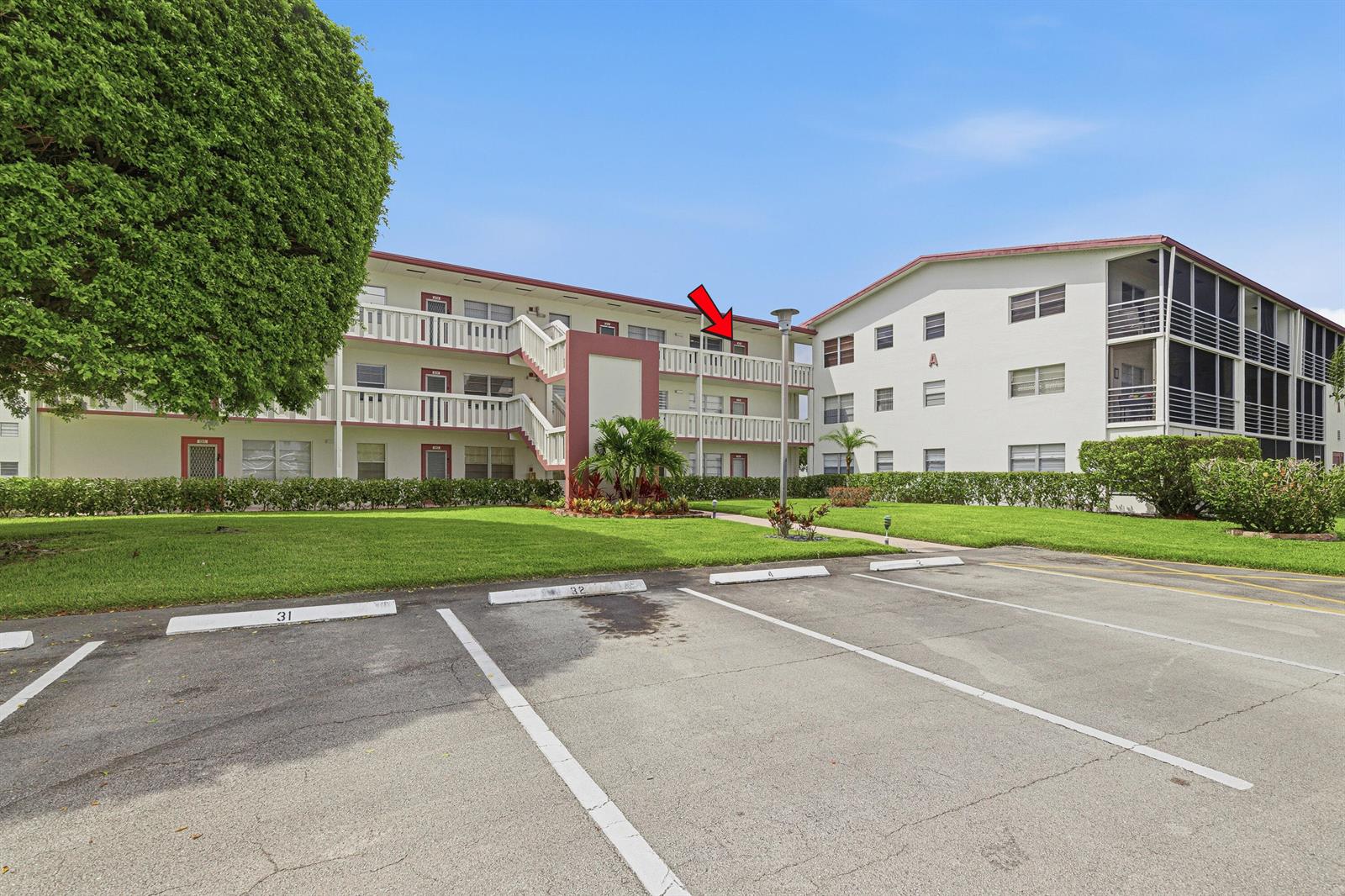 A multi-story apartment building with a red arrow pointing to a third-floor balcony — 32 Fanshaw A # 32, Boca Raton FL 33434, BOCA RATON, FL