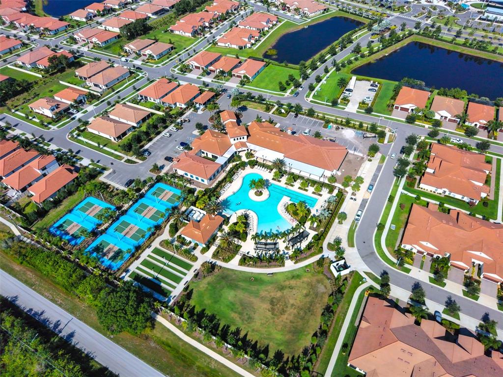 An aerial view of a residential community featuring a central clubhouse, swimming pool, and tennis courts — 5231 WINDY GROVE DRIVE, WIMAUMA, FL