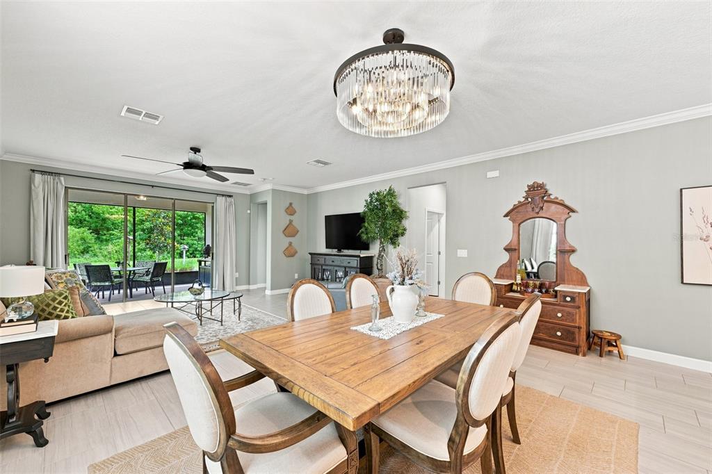 A dining area with a wooden table and chairs sits adjacent to a living room — 5231 WINDY GROVE DRIVE, WIMAUMA, FL