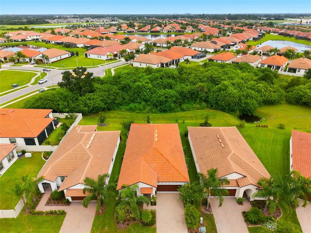 An aerial view shows several suburban houses with orange tile roofs and surrounding green lawns — 5231 WINDY GROVE DRIVE, WIMAUMA, FL