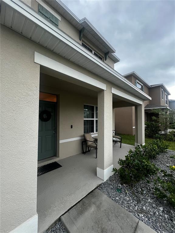 A covered front porch features a green door, concrete flooring, and outdoor seating — 3906 RESTING ROBIN AVENUE, BARTOW, FL