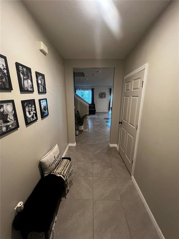 A tiled entryway features a black bench, wall-mounted photo frames, and a doorway leading inside — 3906 RESTING ROBIN AVENUE, BARTOW, FL