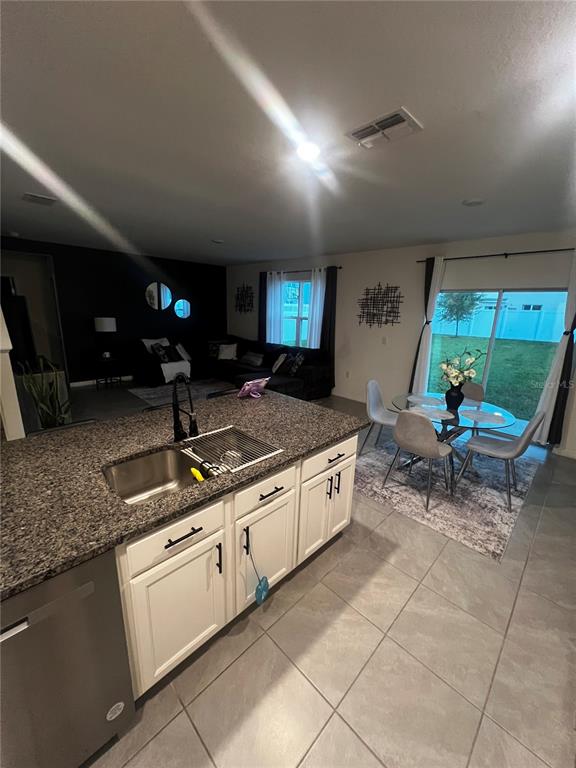 A kitchen with white cabinets and granite countertops overlooks an open-concept living and dining area — 3906 RESTING ROBIN AVENUE, BARTOW, FL