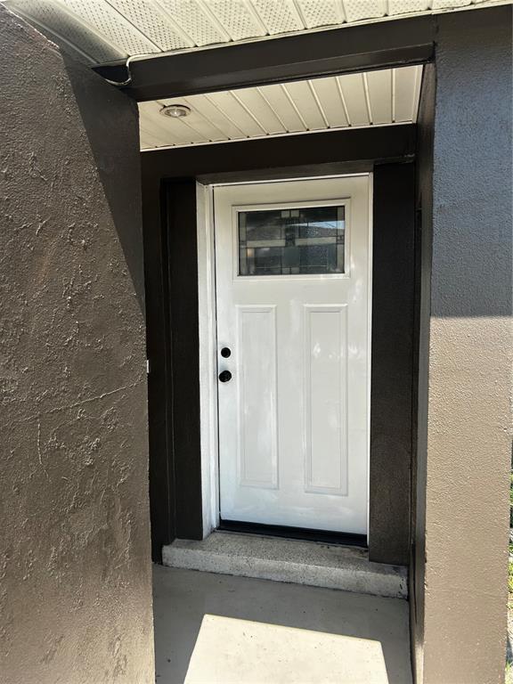 A white front door with a decorative glass window is set within a dark entryway — 7335 GULF HIGHLANDS DRIVE, PORT RICHEY, FL