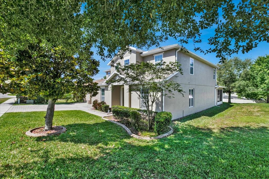 A two-story house with a beige stucco exterior, a paved driveway, and landscaped front yard — 9249 IVYWOOD STREET, CLERMONT, FL