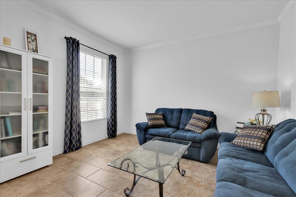 A living room features blue sofas, a glass coffee table, and a white storage cabinet — 9249 IVYWOOD STREET, CLERMONT, FL
