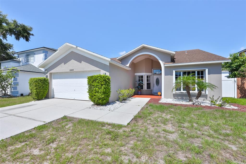 A single-story house with a beige stucco exterior, a two-car garage, and a front entryway — 13403 BEECHBERRY DRIVE, RIVERVIEW, FL