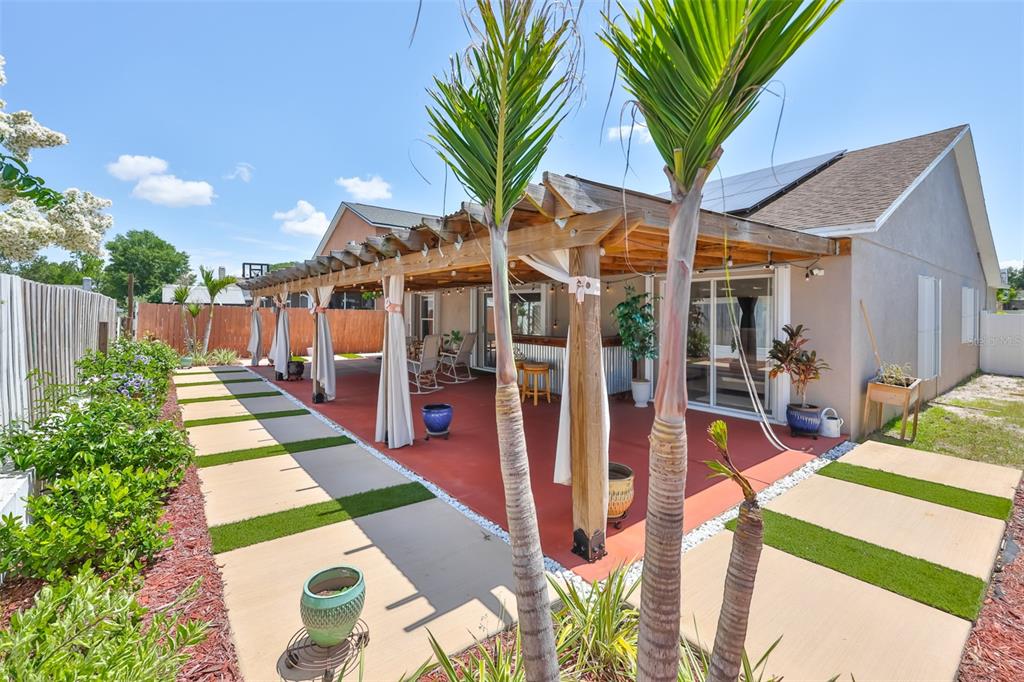 A backyard patio features a wooden pergola, a red concrete floor, and stone pavers — 13403 BEECHBERRY DRIVE, RIVERVIEW, FL