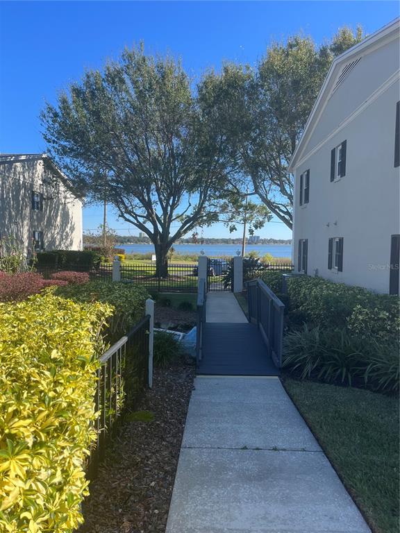 A concrete walkway leads to a small bridge between two apartment buildings overlooking a lake — 689 LAKE HOWARD DRIVE NW UNIT 1E, WINTER HAVEN, FL