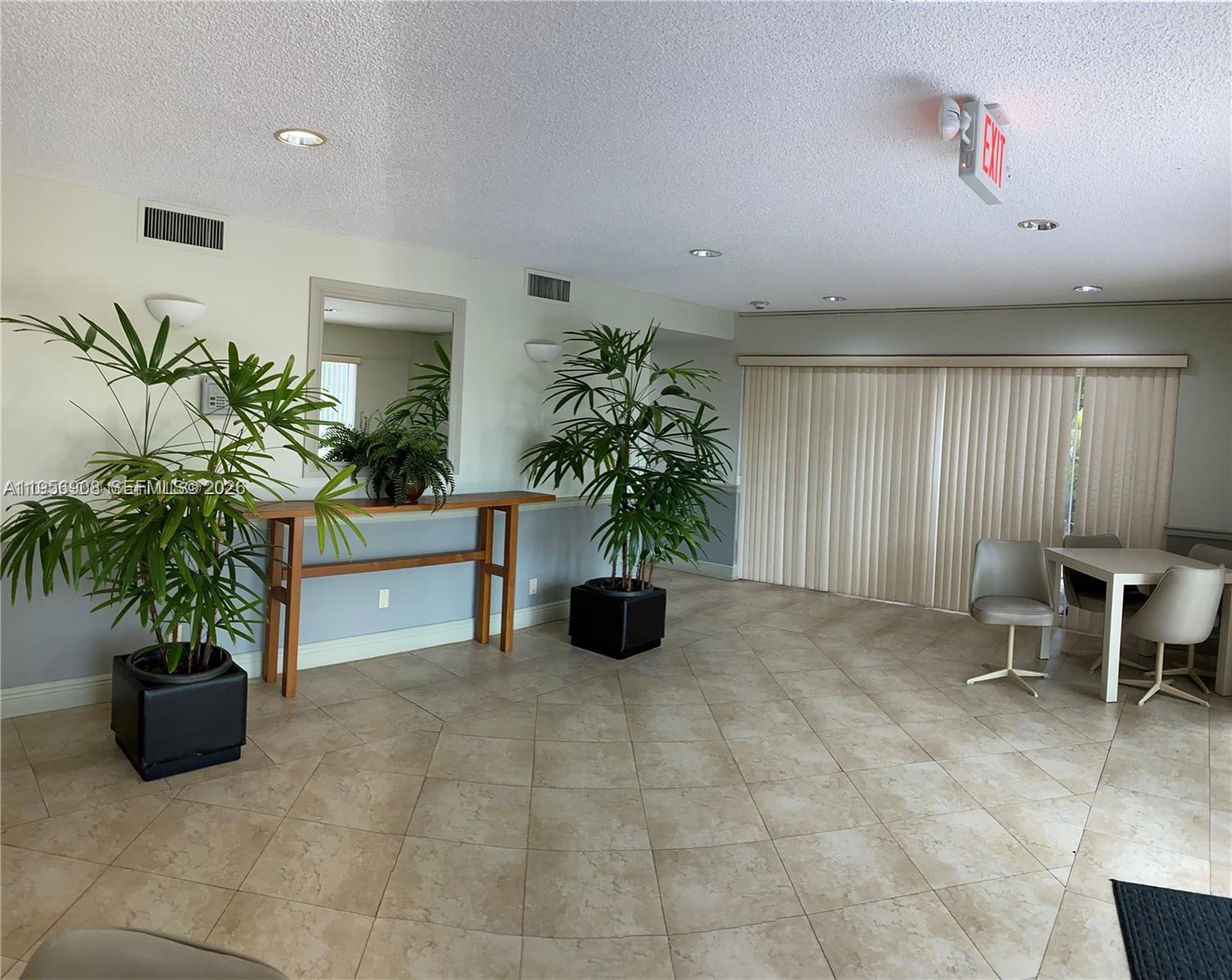 A bright room features tile flooring, two large potted plants, a console table, and seating — 7900 Camino Cir # 403, Miami FL 33143, MIAMI, FL