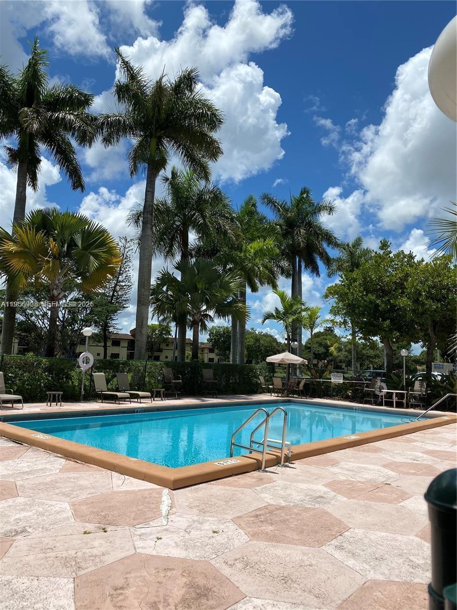 A rectangular swimming pool is surrounded by a paved deck and several tall palm trees — 7900 Camino Cir # 403, Miami FL 33143, MIAMI, FL