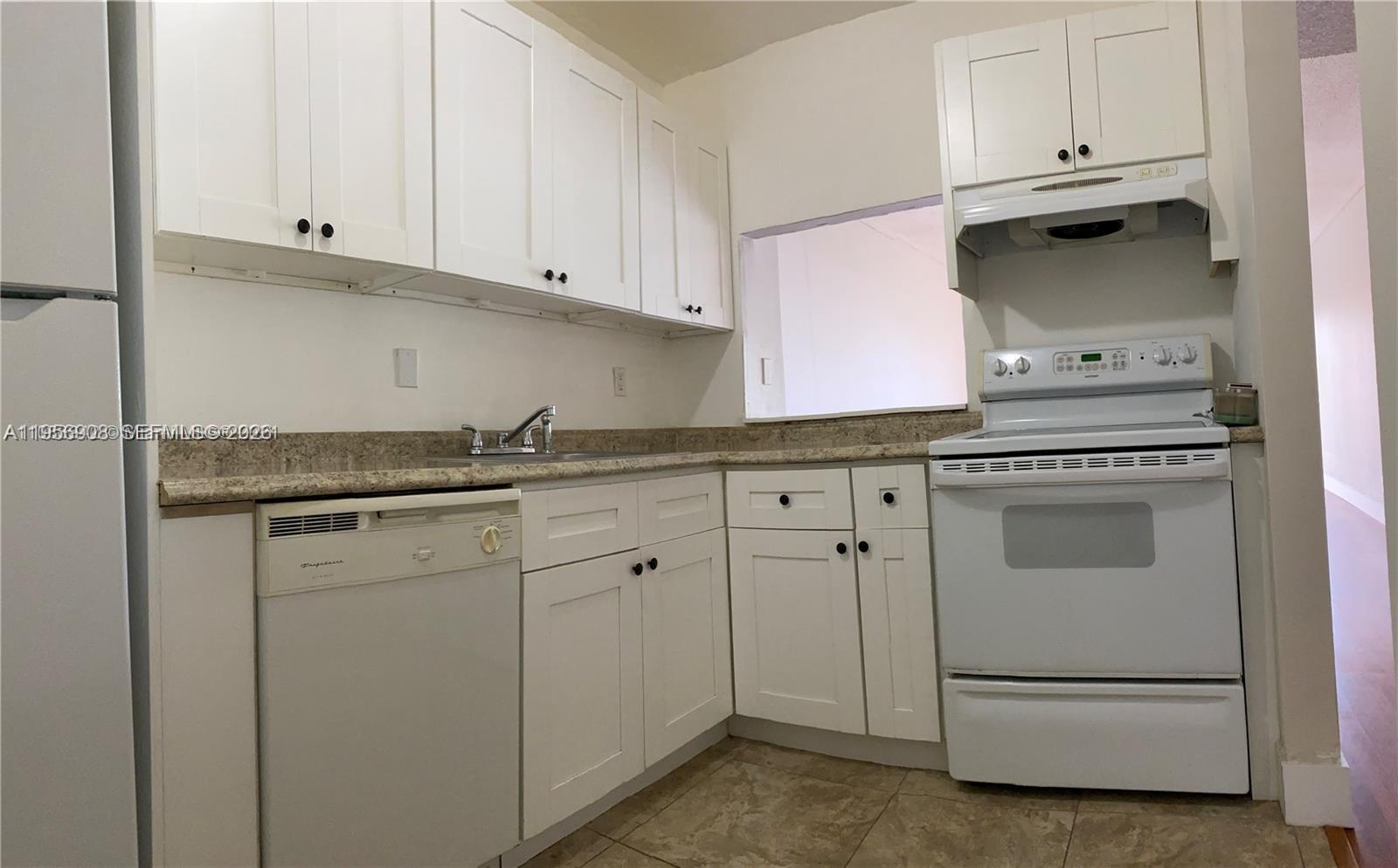 A kitchen features white cabinets, a white stove, a dishwasher, and speckled granite countertops — 7900 Camino Cir # 403, Miami FL 33143, MIAMI, FL