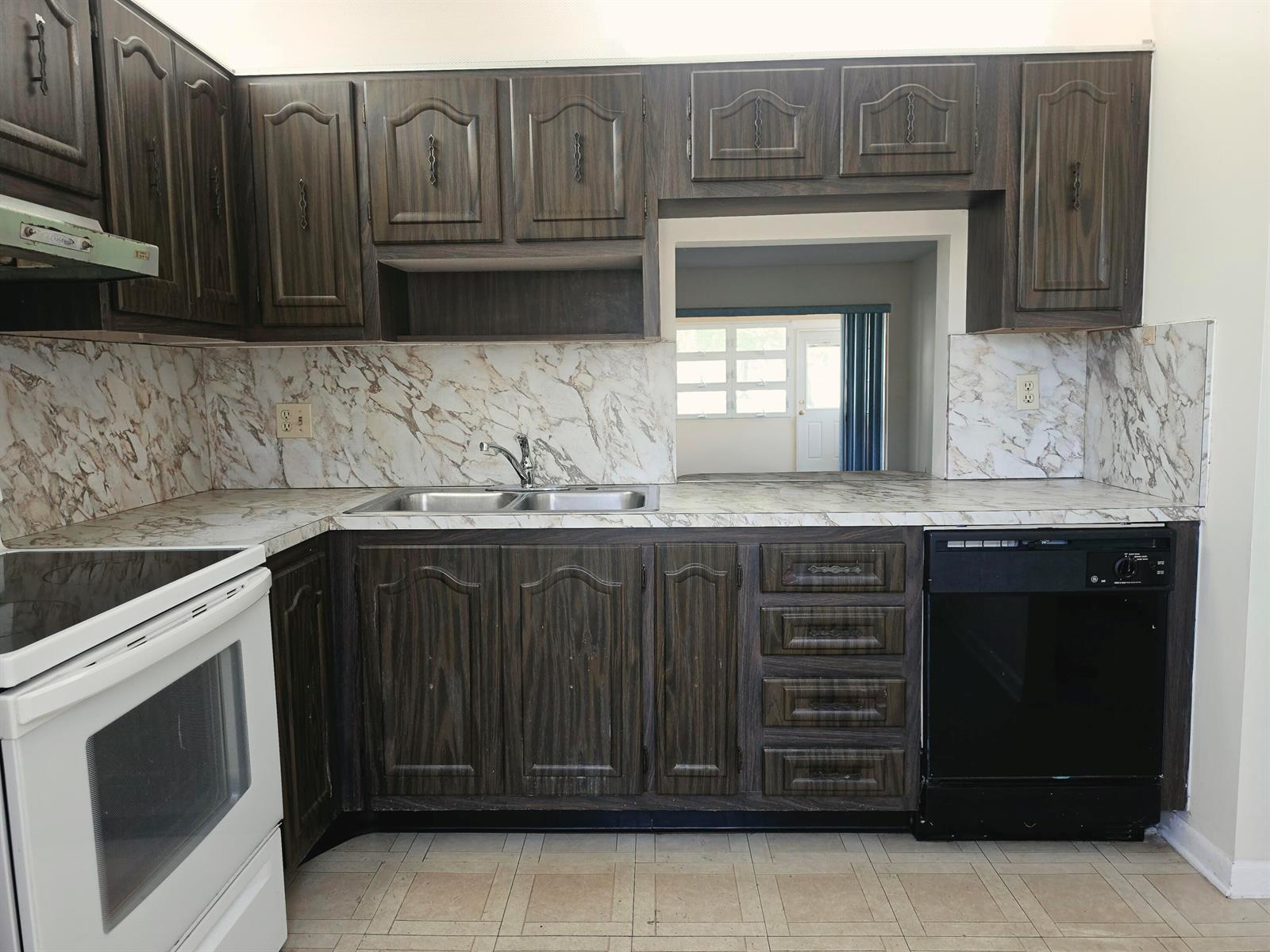A kitchen features dark wood cabinets, marble-patterned countertops, a white stove, and a black dishwasher — 713 Nantucket Circle # B, Lake Worth FL 33467, LAKE WORTH, FL