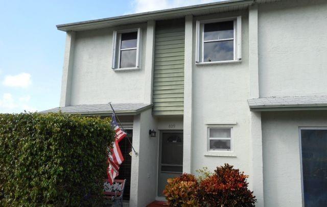 A two-story townhouse exterior with white stucco walls, a green accent panel, and a hedge — 809 Crystal Lake Drive # 809, Deerfield Beach FL 33064, DEERFIELD BEACH, FL