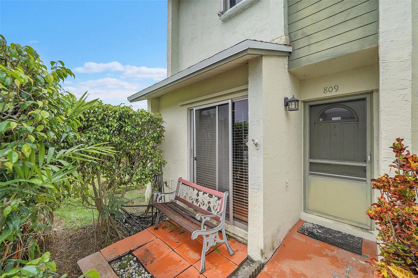 A beige exterior entrance features a sliding glass door, a metal bench, and a screen door — 809 Crystal Lake Drive # 809, Deerfield Beach FL 33064, DEERFIELD BEACH, FL