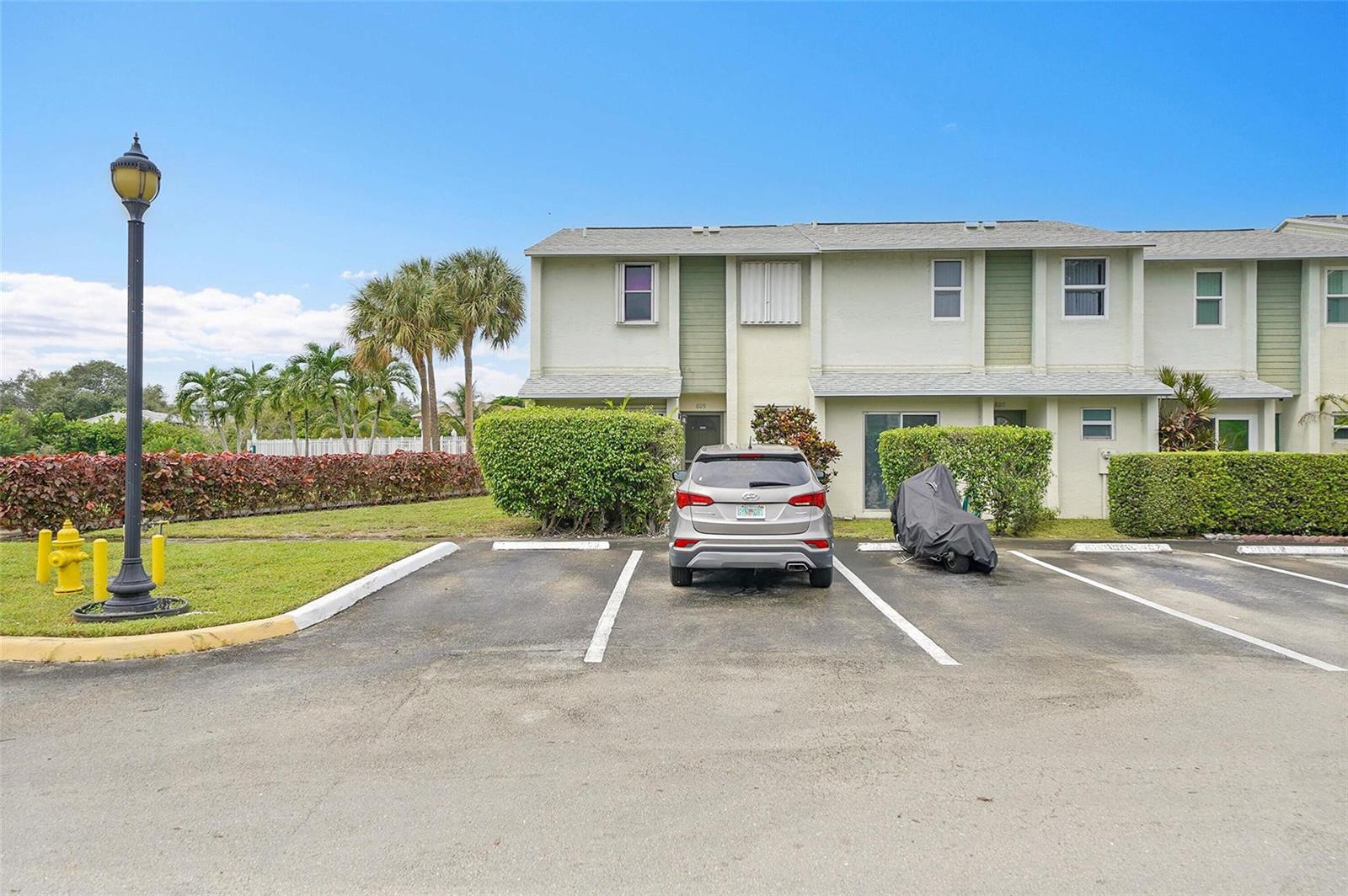 A silver SUV is parked in front of a two-story townhouse with green landscaping — 809 Crystal Lake Drive # 809, Deerfield Beach FL 33064, DEERFIELD BEACH, FL