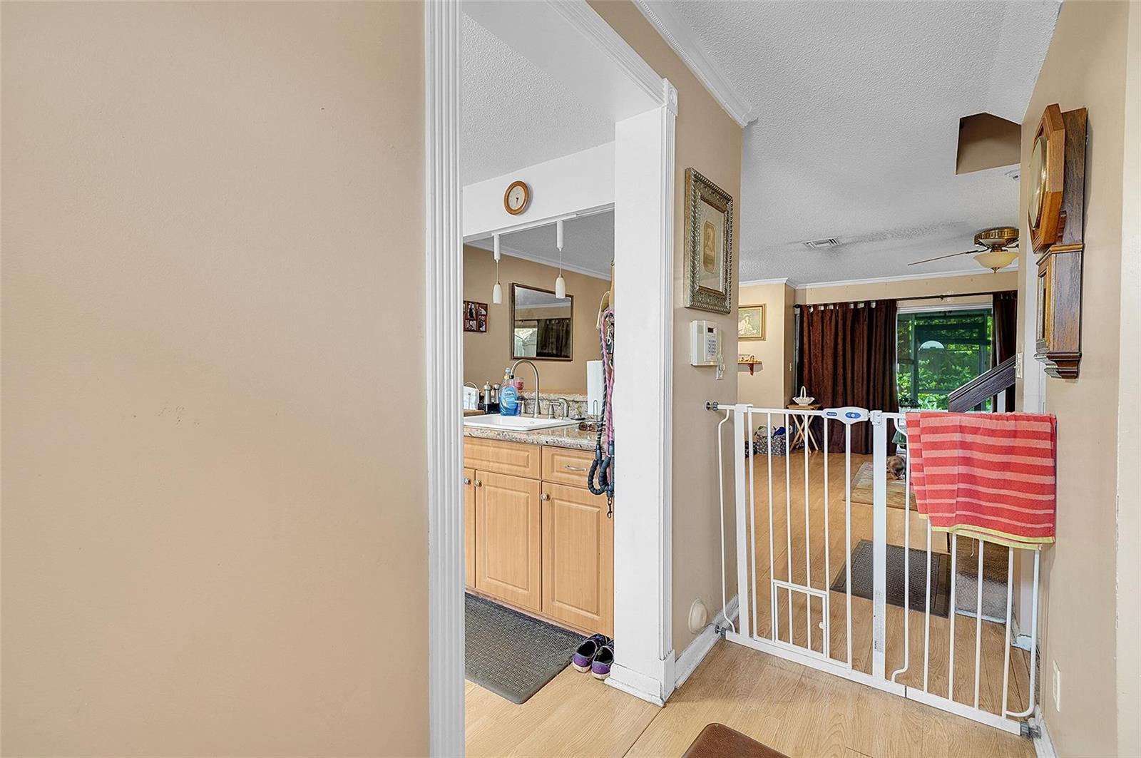 A white baby gate stands in a doorway between a kitchen and a living area — 809 Crystal Lake Drive # 809, Deerfield Beach FL 33064, DEERFIELD BEACH, FL