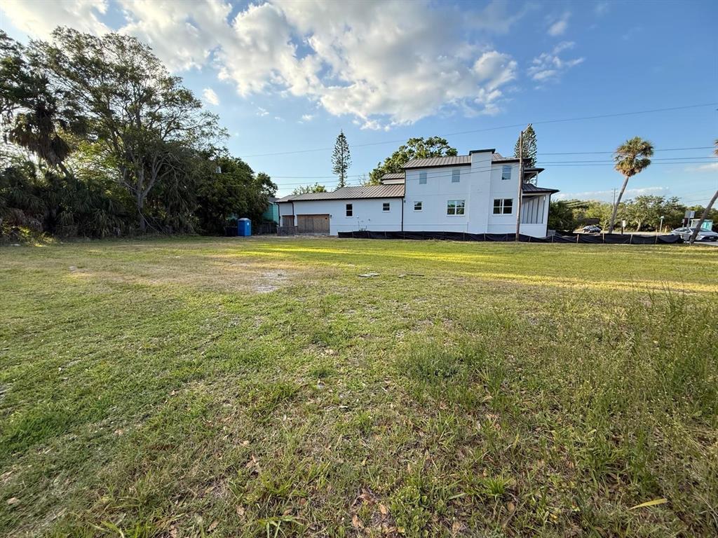 A large, grassy vacant lot sits in front of a newly constructed white house — 3733 6TH STREET S, ST PETERSBURG, FL