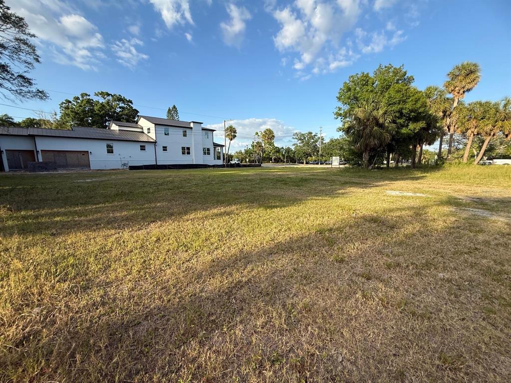 A large, grassy vacant lot sits adjacent to a modern white two-story house — 3733 6TH STREET S, ST PETERSBURG, FL