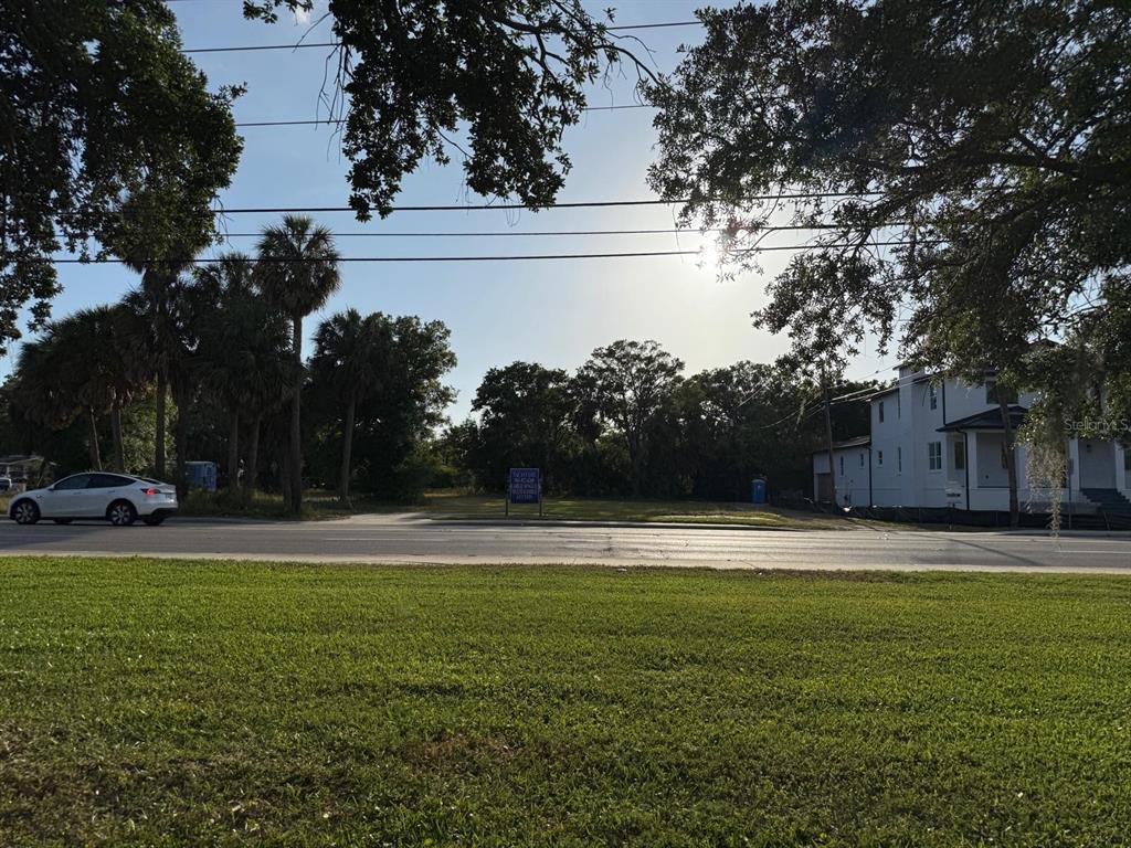 A vacant lot sits between a white house and palm trees along a paved road — 3733 6TH STREET S, ST PETERSBURG, FL