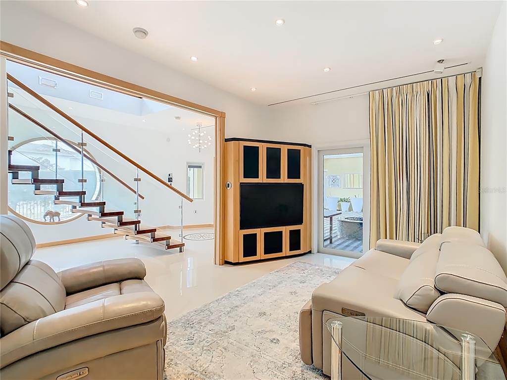 A living room features a floating staircase, a television cabinet, and a beige leather sofa — 917 DESERT MOUNTAIN COURT, REUNION, FL