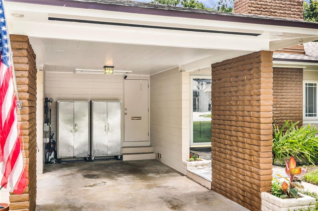 A covered carport features a concrete floor, two metal storage cabinets, and brick pillars — 1215 DELANEY PARK DRIVE, ORLANDO, FL