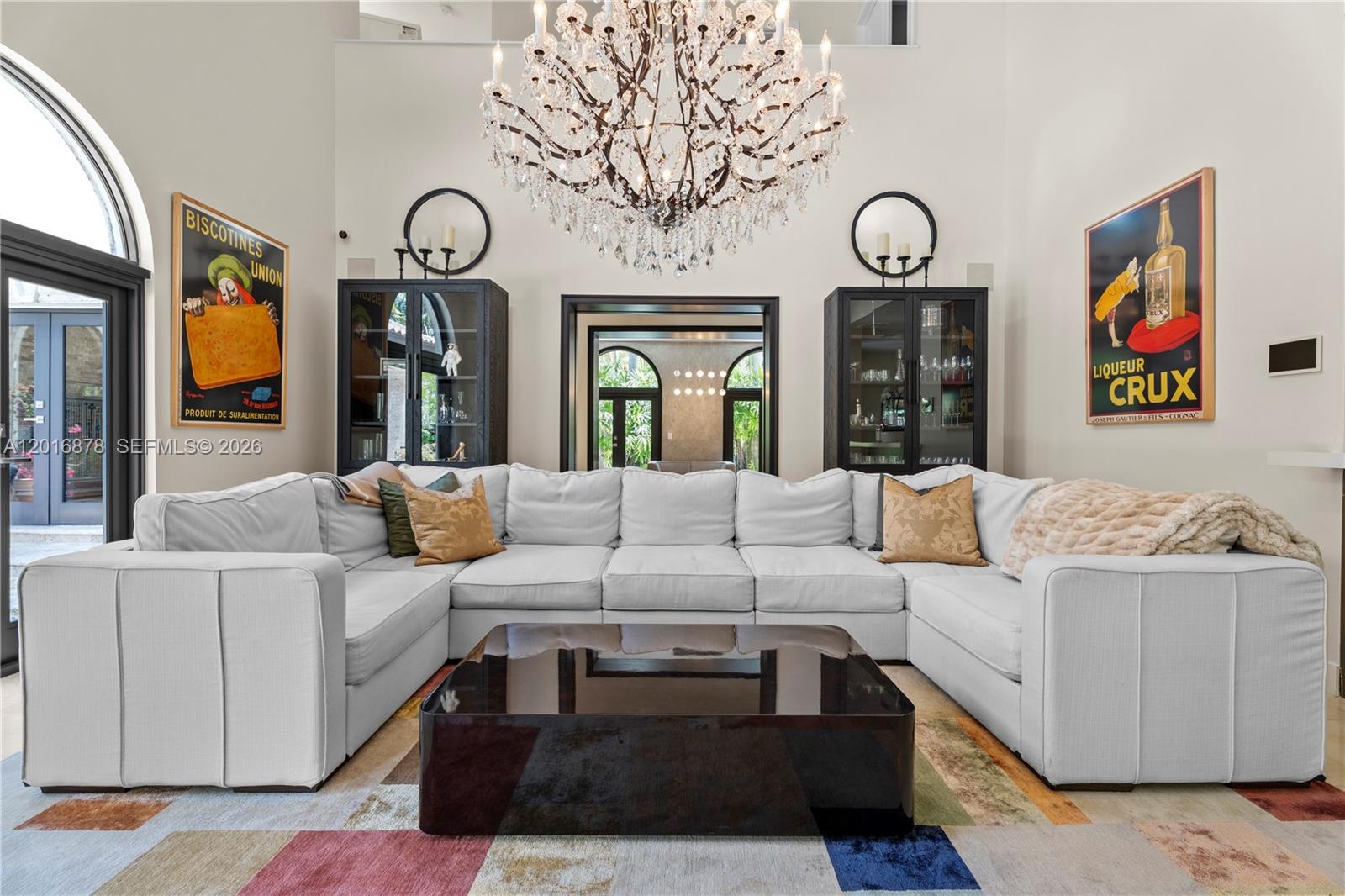 A living room features a large white sectional sofa, a dark coffee table, and a chandelier — 8550 Old Cutler Rd, Coral Gables FL 33143, CORAL GABLES, FL