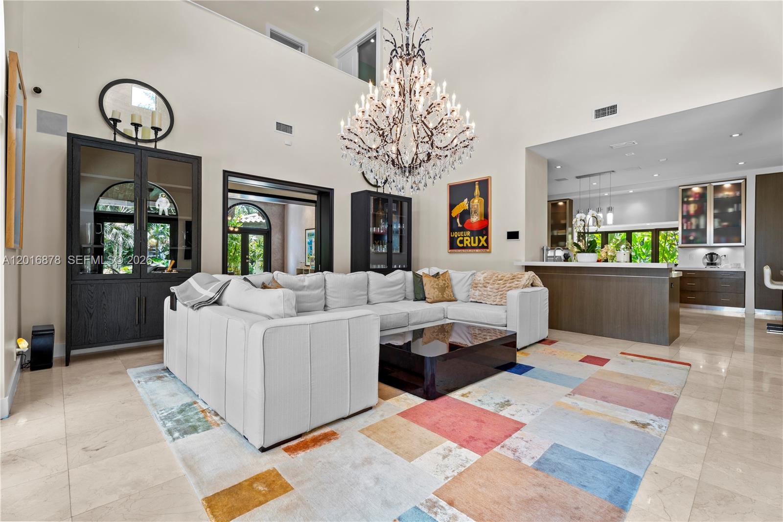 A living room features a large sectional sofa, a crystal chandelier, and a colorful rug — 8550 Old Cutler Rd, Coral Gables FL 33143, CORAL GABLES, FL
