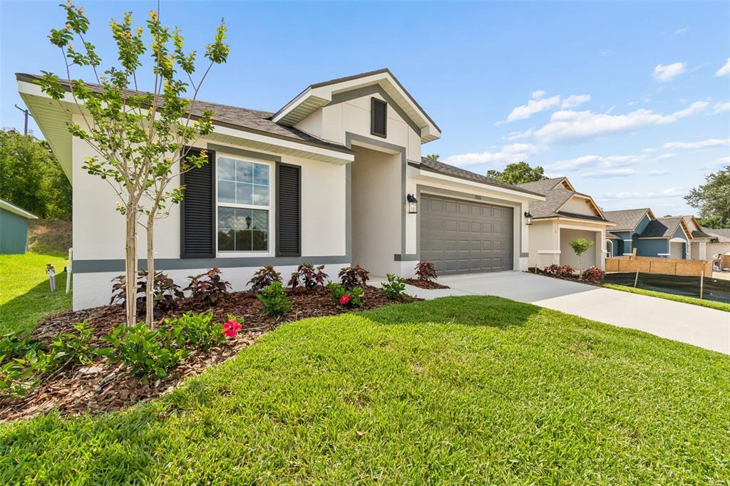 A single-story house with a white stucco exterior, dark shutters, and a two-car garage — 13000 KENT BRADLEY STREET, DADE CITY, FL