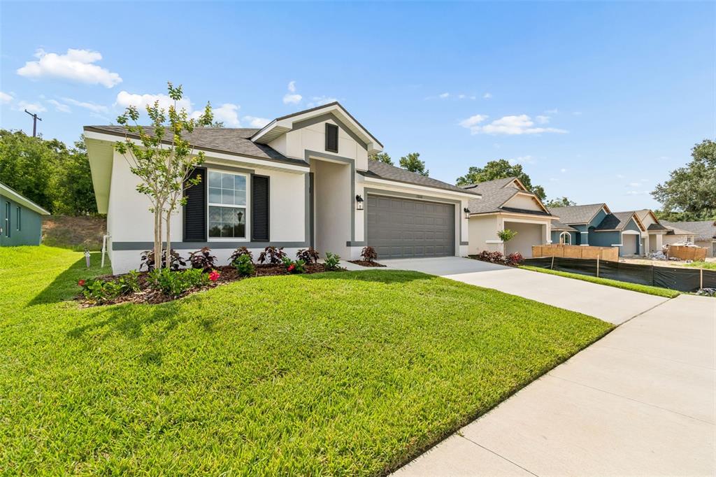 A single-story house with a white stucco exterior, gray trim, and a two-car garage — 13000 KENT BRADLEY STREET, DADE CITY, FL