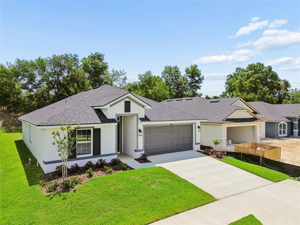 A single-story house with a white stucco exterior, gray trim, and a two-car garage — 13000 KENT BRADLEY STREET, DADE CITY, FL