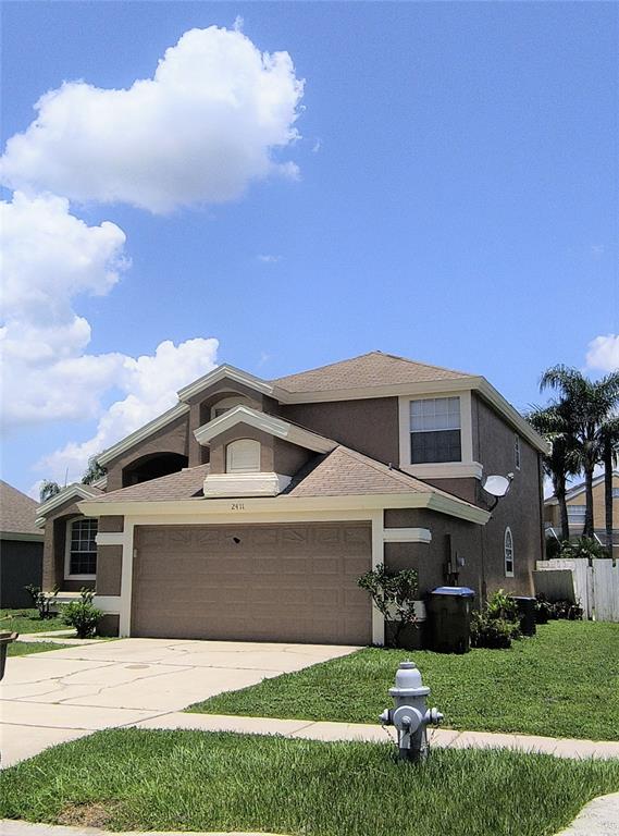 A two-story house with a brown stucco exterior, a two-car garage, and a fire hydrant — 2411 BERKSHIRE COURT, KISSIMMEE, FL