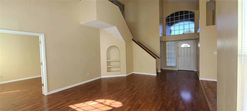 An open living area features high ceilings, wood-look flooring, a staircase, and an arched niche — 2411 BERKSHIRE COURT, KISSIMMEE, FL