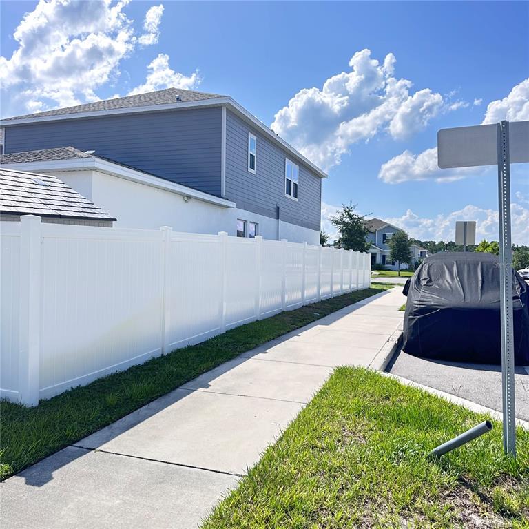 A white vinyl fence runs alongside a sidewalk next to a two-story house — 6459 PINE FORK ALLEY, ST CLOUD, FL