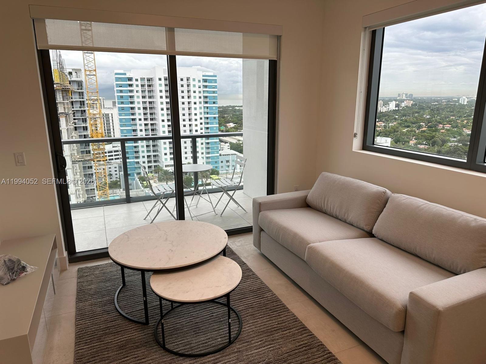 A living room features a light-colored sofa, nesting coffee tables, and a balcony with views — 239 SW 9th St # 2002, Miami FL 33130, MIAMI, FL