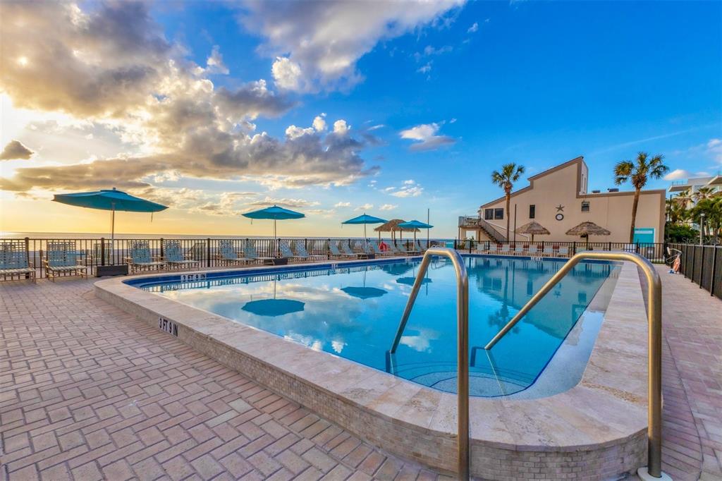 An outdoor swimming pool with lounge chairs and umbrellas overlooks the beach at sunset — 4621 GULF OF MEXICO DRIVE UNIT 10D, LONGBOAT KEY, FL