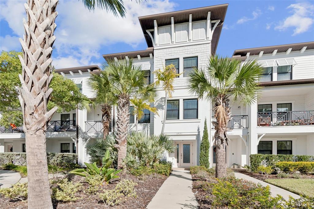 A three-story white townhouse exterior features palm trees, balconies, and a central front entrance — 4921 W PAUL AVENUE UNIT 4, TAMPA, FL