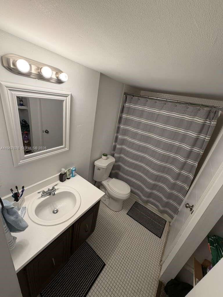 A bathroom features a vanity with a white countertop, a toilet, and a shower curtain — 488 NW 165th St Rd # 614, Miami FL 33169, MIAMI, FL