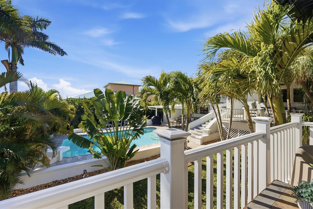 A view from a balcony overlooking a swimming pool surrounded by palm trees and landscaping — 217 BANGSBERG ROAD SE, PORT CHARLOTTE, FL