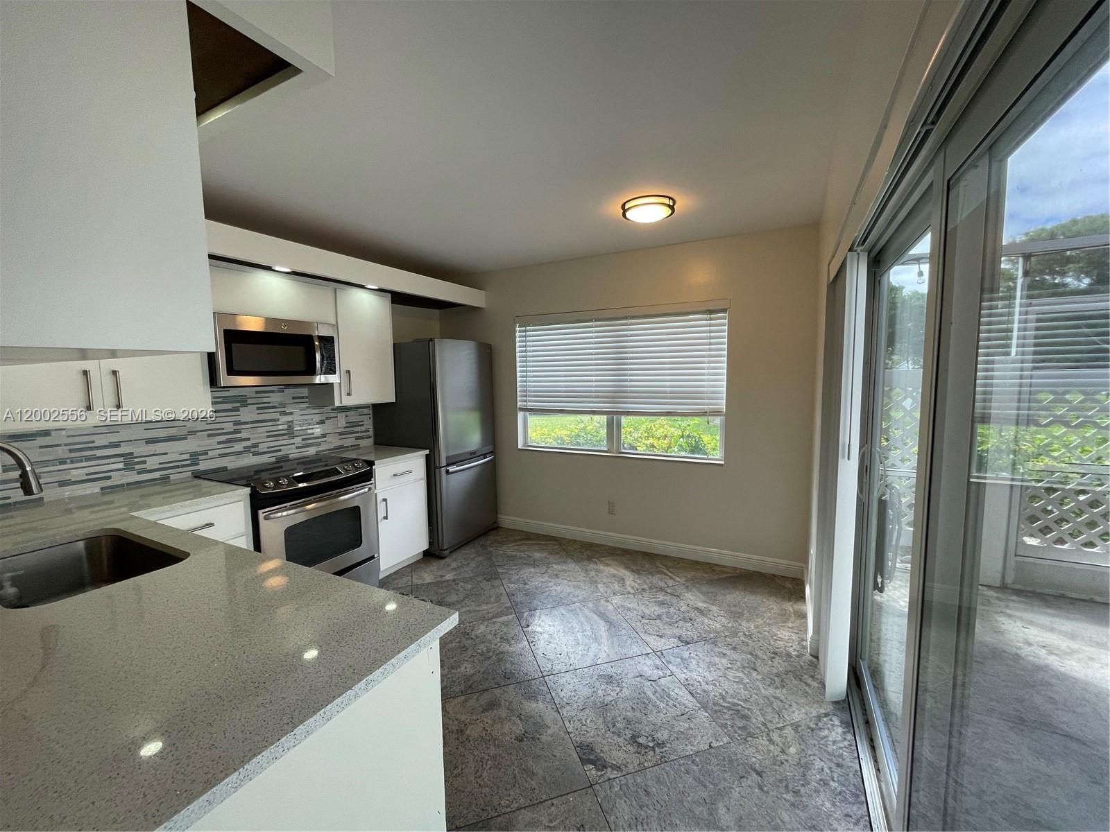 A dining area with a dark wood table and chairs sits adjacent to a kitchen — 5801 Wheatley Ct, Boynton Beach FL 33436, BOYNTON BEACH, FL